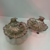A pair of George V silver bon bon dishes as scallop shells each raised on three feet (Birmingham