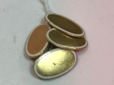 A pair of 18 carat gold and white enamel decorated oval cufflinks of plain form 7.