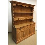 A modern pine dresser, the boarded two tier plate rack with six small drawers over three drawers and