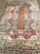 A Caucasian rug, the central panel set with three medallions on an orange and cream geometric