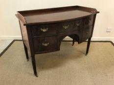 An Edwardian mahogany bow fronted sideboard, the plain top with cross-banded edging over two central