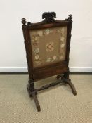 An early Victorian rosewood framed fire screen with needlework panel (formerly adjustable now