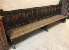 A circa 1900 oak park type bench or settle, the panelled back above a slatted seat on end trestle