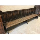 A circa 1900 oak park type bench or settle, the panelled back above a slatted seat on end trestle