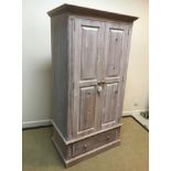 A modern limed pine two door wardrobe, with single drawer on a plinth base, 95 cm wide x 58 cm