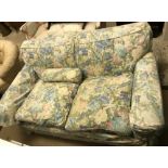 A circa 1900 upholstered two seat sofa with pale floral loose covers, approx 158 cm wide x 90 cm