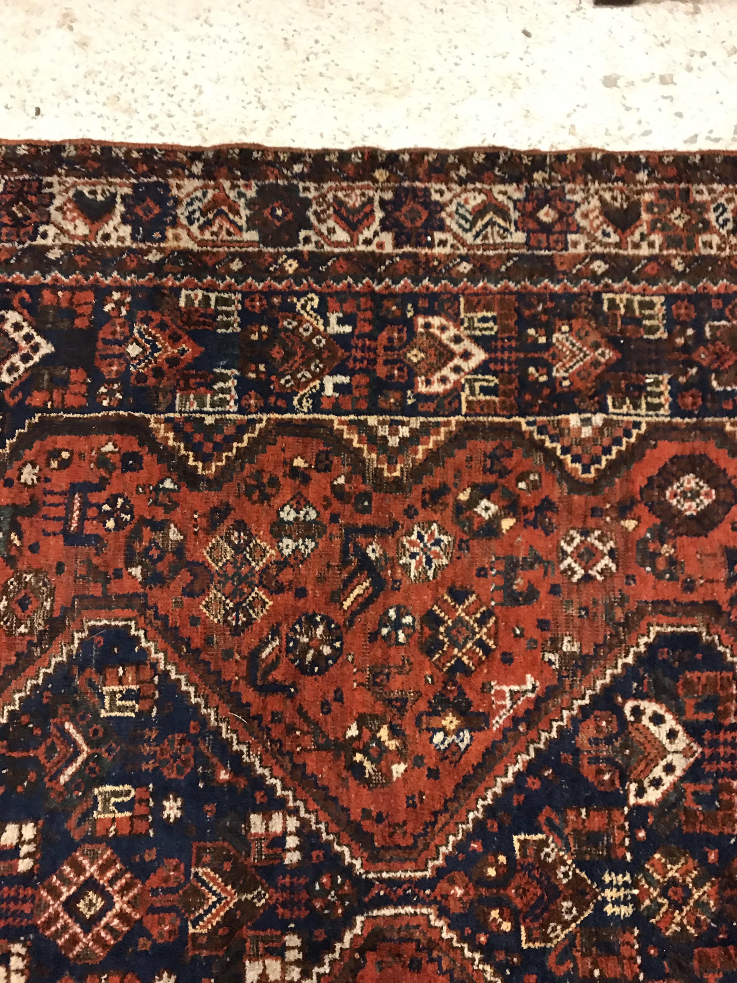 A Shiraz carpet, the central panel set with three joined diamond shaped medallions on a red and blue - Image 9 of 17