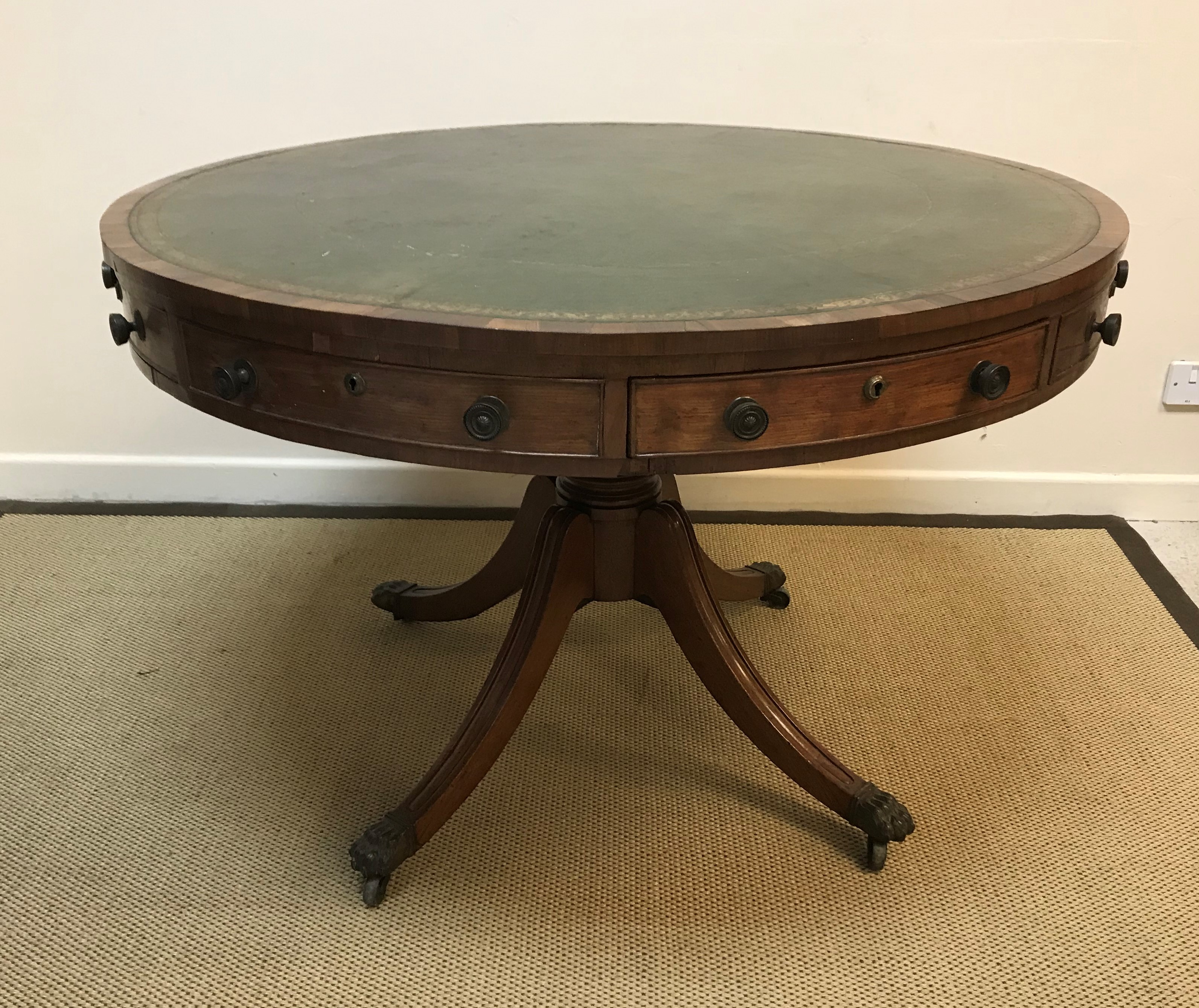 A Regency mahogany drum table, the top with tooled and gilded leather insert over four real and four