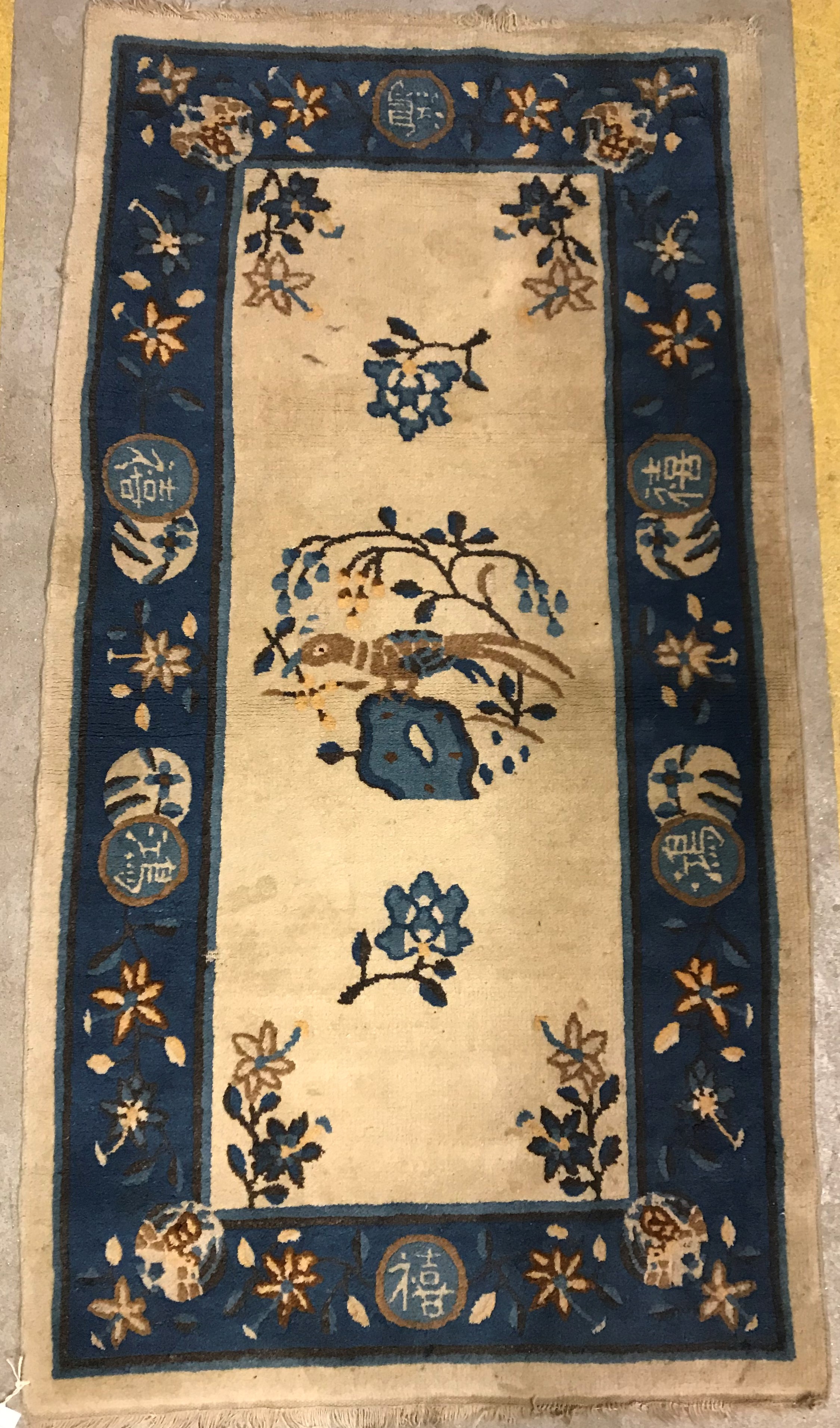 A 1950's Chinese rug, the central panel set with floral sprays and bird decoration on a cream