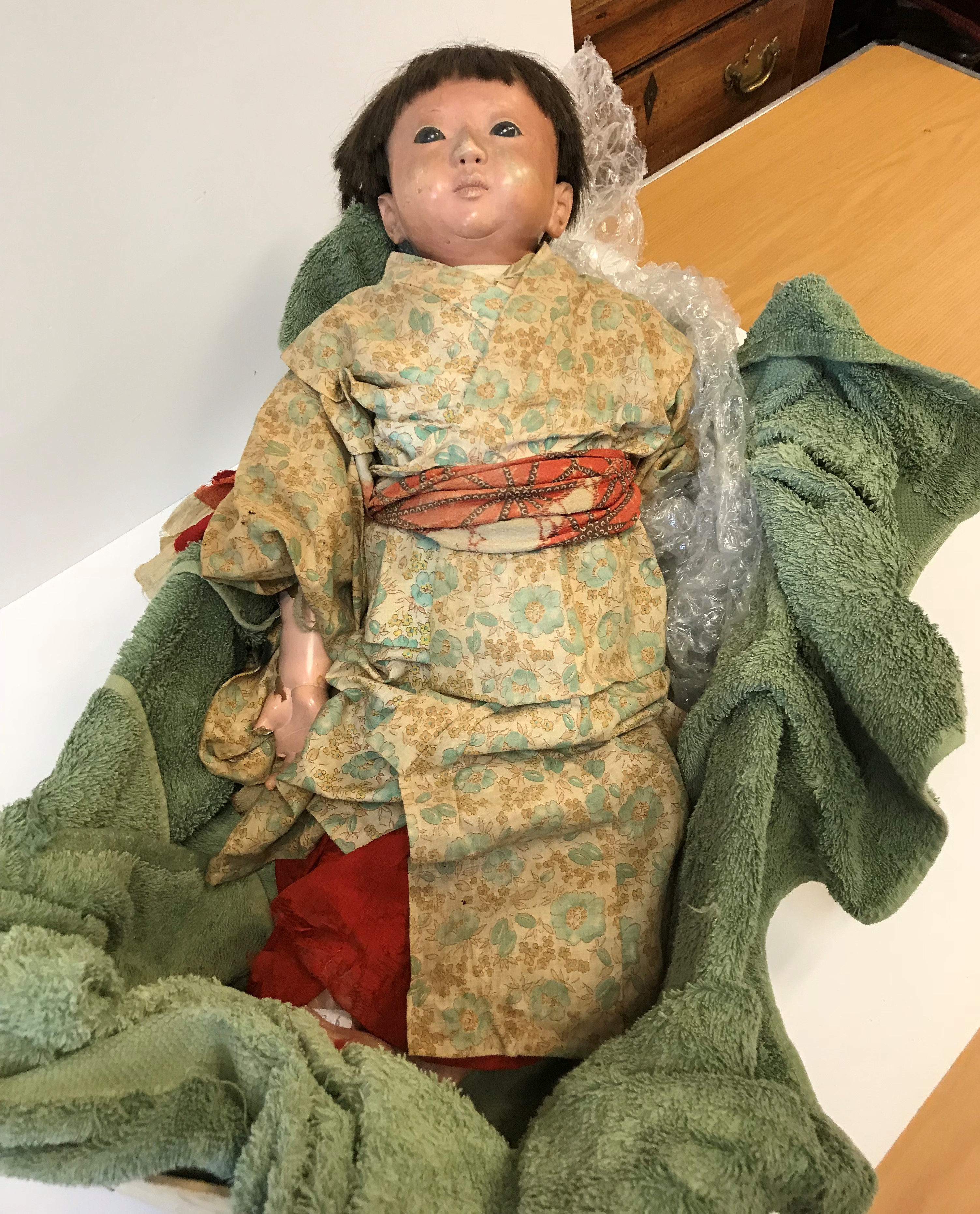 A late 19th / early 20th Century Japanese composition doll with flesh colour painted face and real