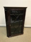 An early 19th Century mahogany hanging corner cabinet, the moulded cornice with lozenge inlaid