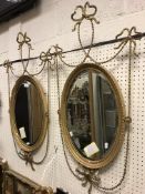 A pair of circa 1900 gilt and gesso framed oval wall mirrors with fine harebell drape and ribbon