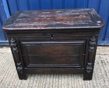 An oak coffer or chest, the plank top with pleated ends over a panelled front and sides with applied