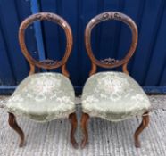 A set of six Victorian walnut balloon back dining chairs with upholstered seats on turned and fluted