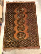A Bokhara type rug set with repeating medallions on a burnt orange ground, within a stepped burnt