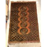 A Bokhara type rug set with repeating medallions on a burnt orange ground, within a stepped burnt