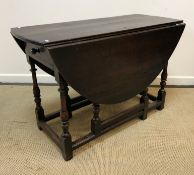An 18th Century oak oval gate-leg drop-leaf dining table on turned and ringed supports to block feet