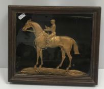 A framed and glazed gilt brass and engraved cast figure of "Jockey on horseback", 36 cm x 26 cm