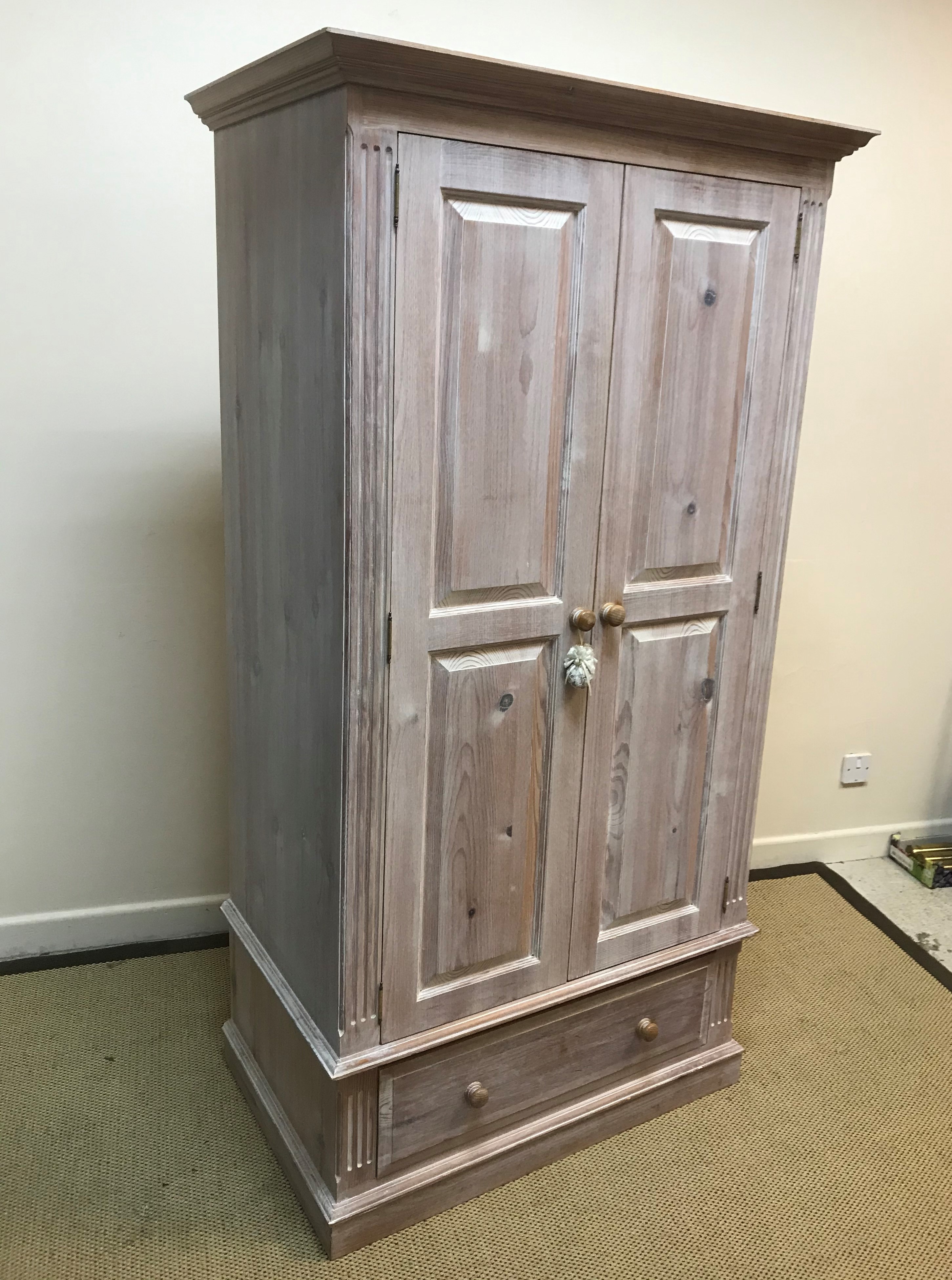 A modern limed pine two door wardrobe, with single drawer on a plinth base, 95 cm wide x 58 cm