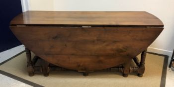 A 20th Century walnut oval double gate-leg dining table in the 18th Century manner, raised on turned