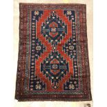 A Kasak rug, the central panel set with two repeating medallions on a red ground with stylised