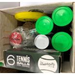 A box containing various tennis balls, squash balls, hockey balls, etc