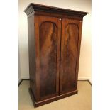 A Victorian mahogany wardrobe, the moulded cornice over two arched panelled doors enclosing a