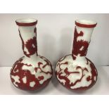 A pair of Peking glass vases of onion form in red and white with blossom, tiger and dragon