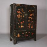 A Chinoiserie ebonised cabinet having two doors above a panel decorated with archaic symbols, the