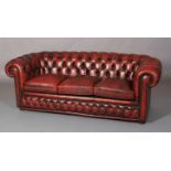 An ox-blood button back leather Chesterfield, close-nailed, three seater, on bun feet, approximately