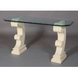 A bevelled glass console table on cast stone-effect twin scroll base rectangular with cut corners,