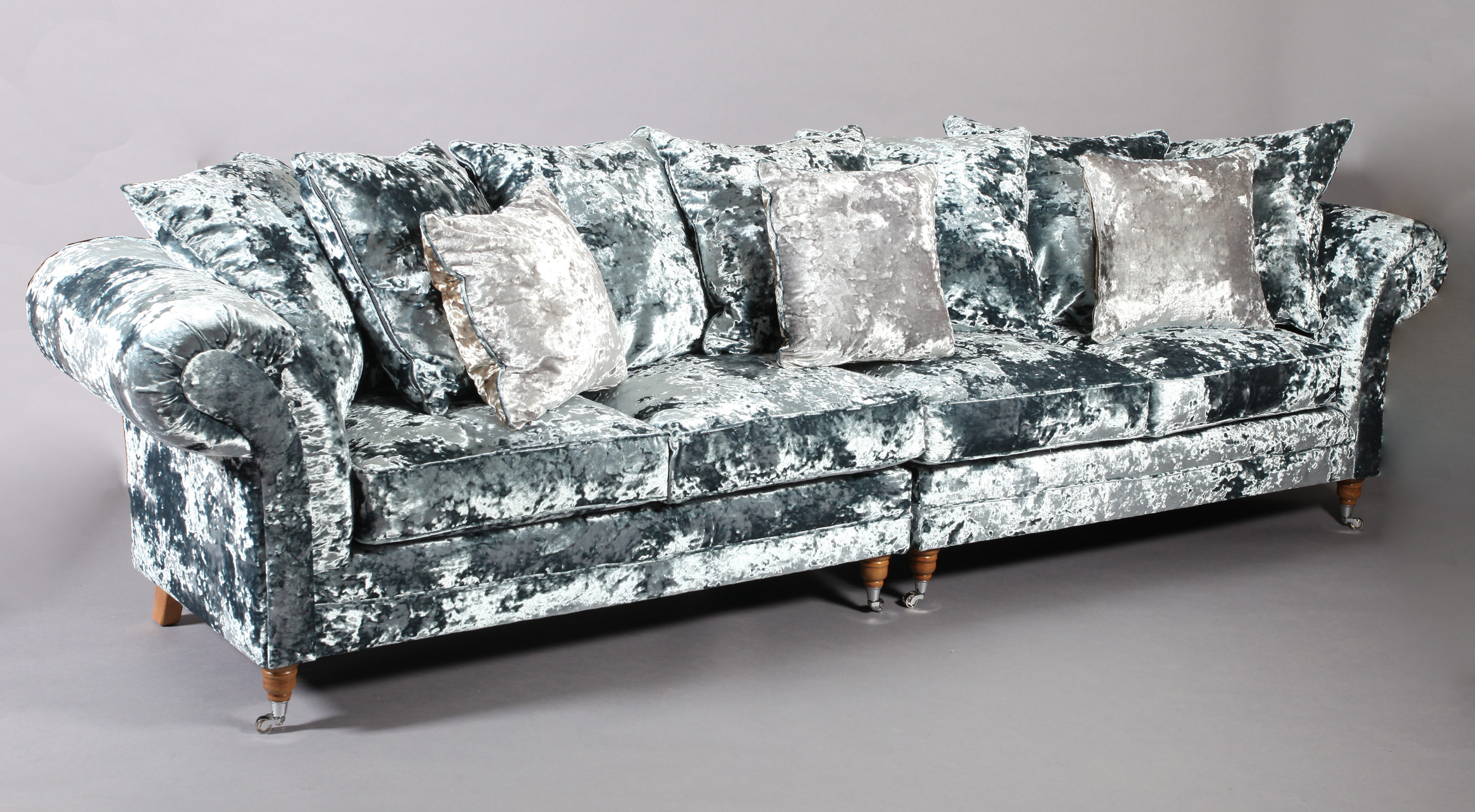 A four seater sofa upholstered in pale blue crushed velvet, on turned legs with chrome castors,