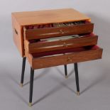 A teak three drawer chest canteen c.1950's on ebonised rounded legs, containing an extensive suite