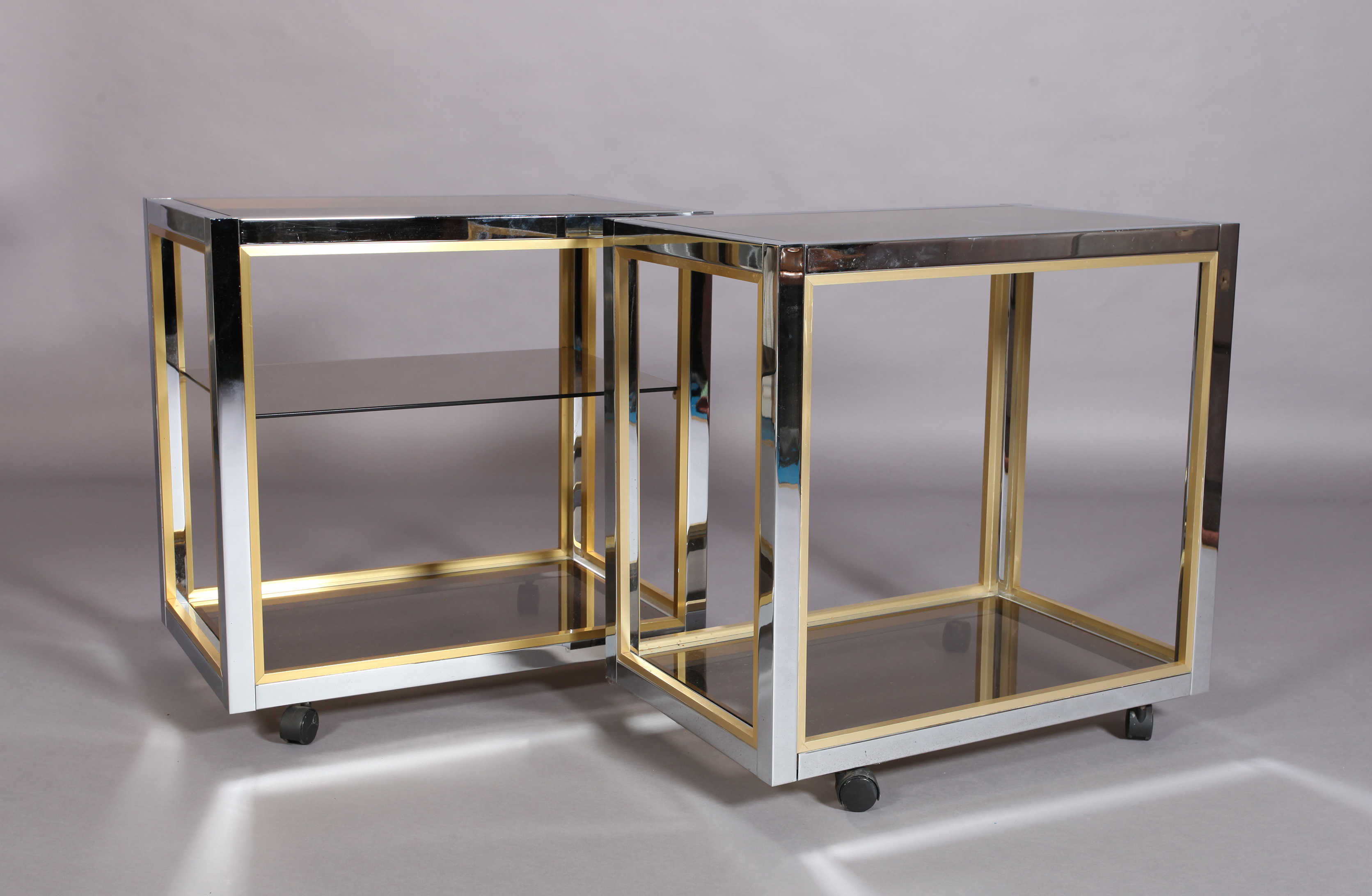 A pair of vintage brass and chromium plated drinks trolleys with smoked glass shelves, one with