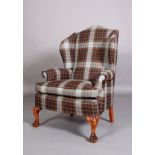 A Georgian style winged armchair, duck egg blue and brown tartan upholstery, on foliate carved