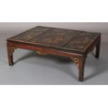 A chinoiserie black lacquered and gilt coffee table, rectangular the triple panelled top painted