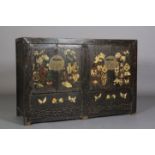 A Chinoiserie ebonised cabinet having two pairs of doors decorated with archaic symbols with brass