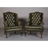A pair of button back green leather winged armchairs, with close nail studding, on cabriole legs