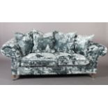 A three seater sofa upholstered in pale blue crushed velvet, on turned legs with chrome castors,