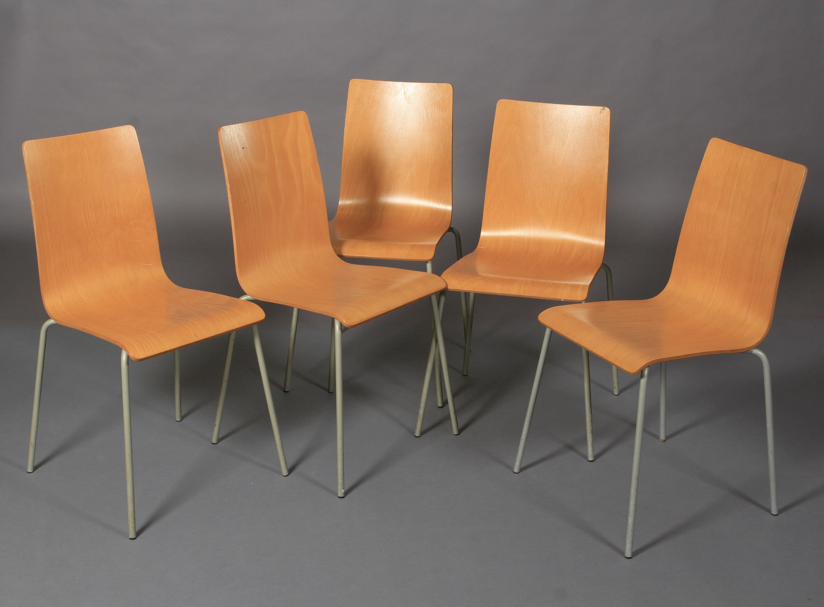 A set of five beech laminate stacking chairs on pale grey tubular legs