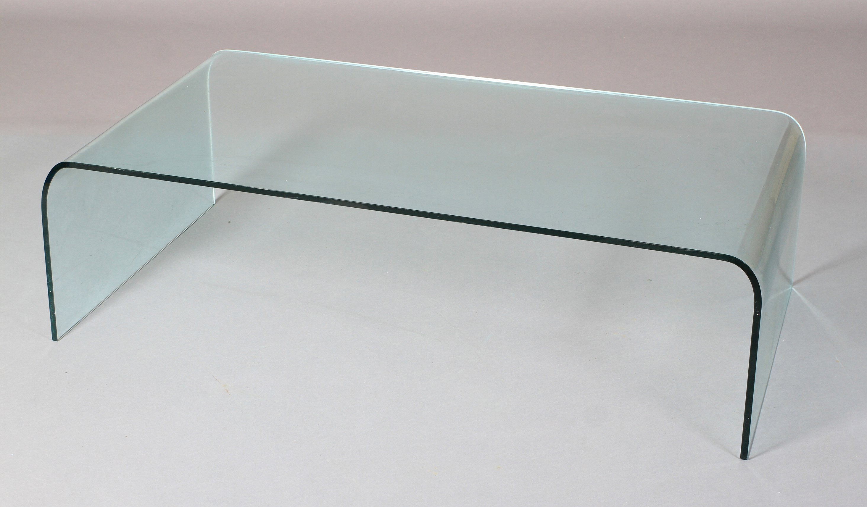 A curved glass coffee table 130cm long x 69cm wide x 38cm high