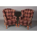 A pair of button back winged armchairs upholstered in aubergine and pale green plaid, close