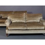 A pair of champagne velour two seater sofas, with seat and back cushions, on square tapered legs