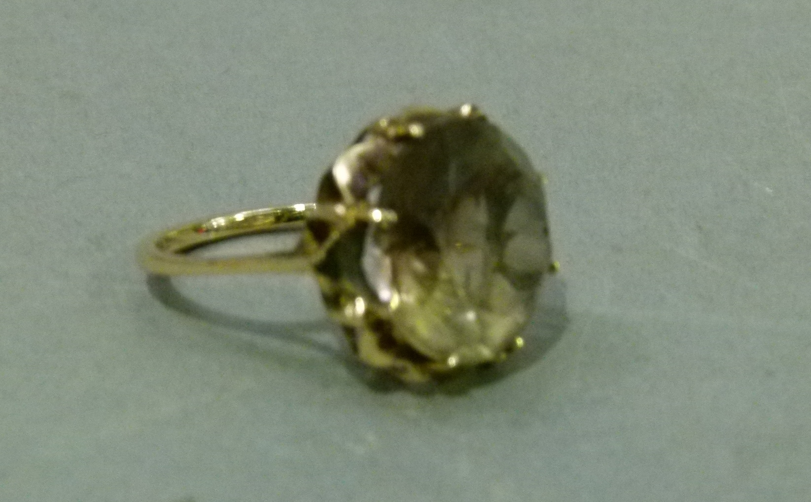 A smoky quartz dress ring in 9ct gold, the circular faceted stone claw set, raised against a star