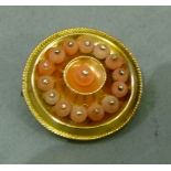 A mid-Victorian coral set shield brooch in 15ct gold, the 3mm coral beads post mounted to the centre