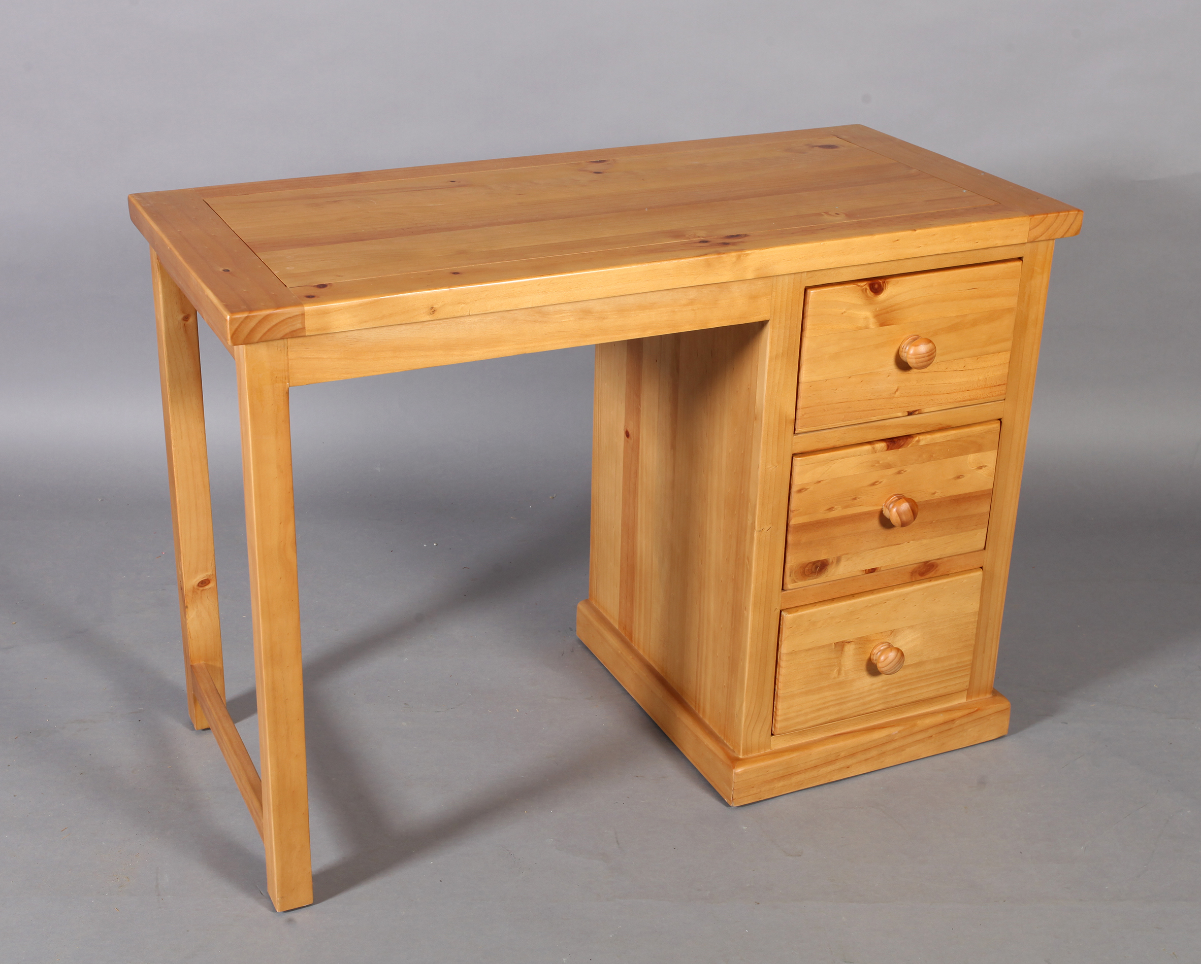 A reproduction pine single pedestal desk with kneehole flanked by three short drawers, rectangular