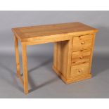 A reproduction pine single pedestal desk with kneehole flanked by three short drawers, rectangular