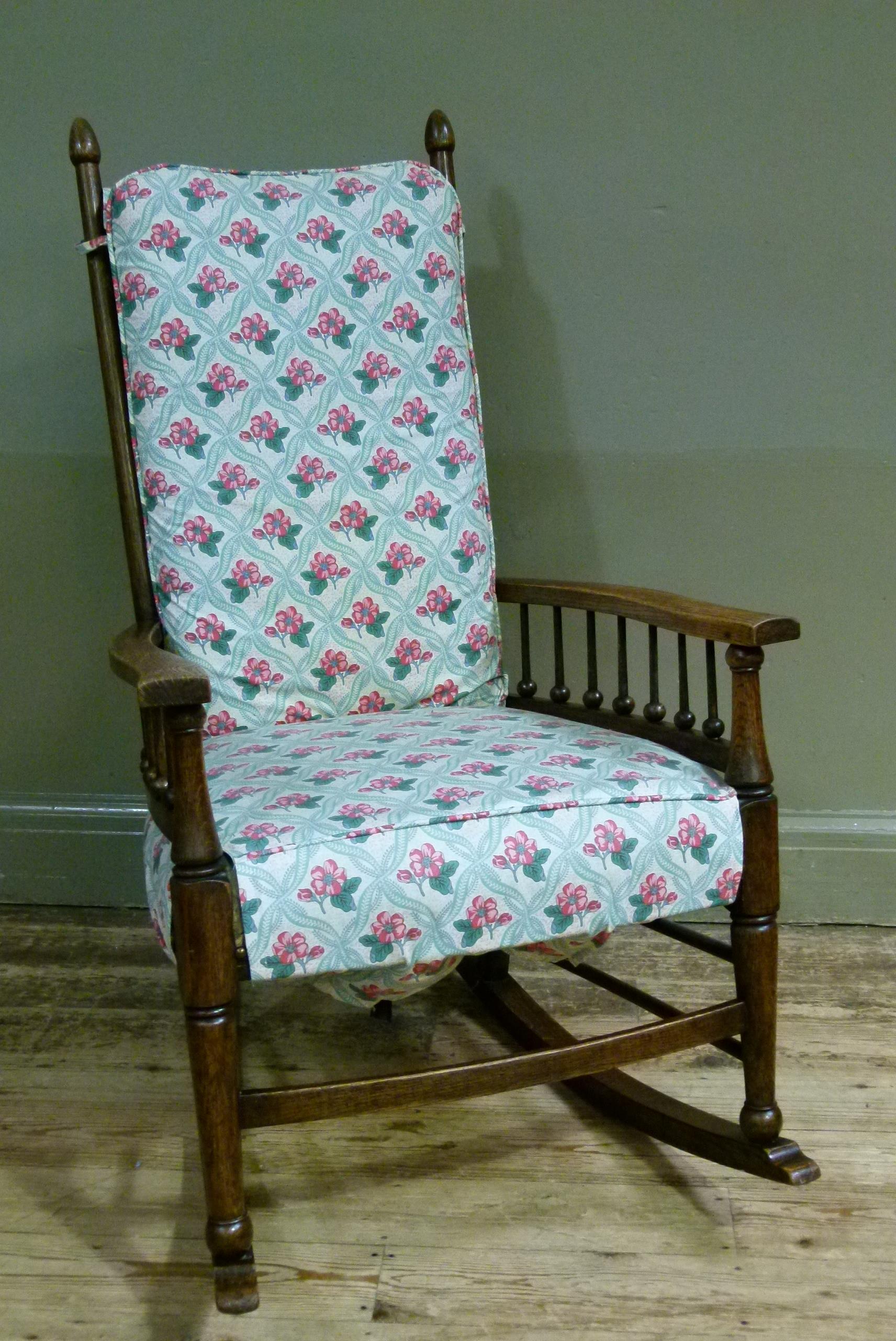 An early 20th century elm rocking chair having a ladder back and spindle arms upholstered pad to the