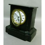 A Victorian black slate mantel clock, the breakfront case above a circular glass bezel inclosing a