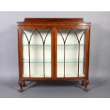 A walnut veneered display cabinet enclosed by a pair of doors with arched glazing bars, glass